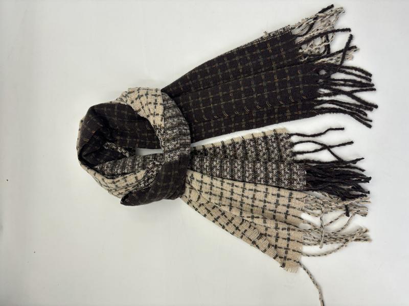 Folded two-tone plaid woven scarf in black and beige with fringe ends, laid flat on white background