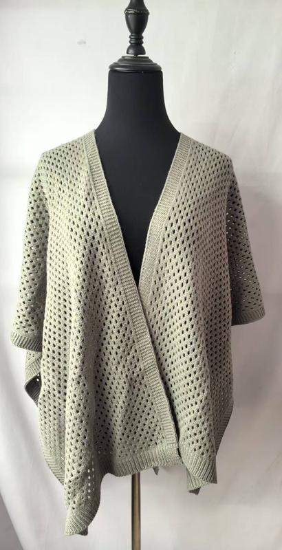 Sage green open-weave knit oversized cardigan wrap displayed on black dress form mannequin, showing loose crochet pattern and short sleeves