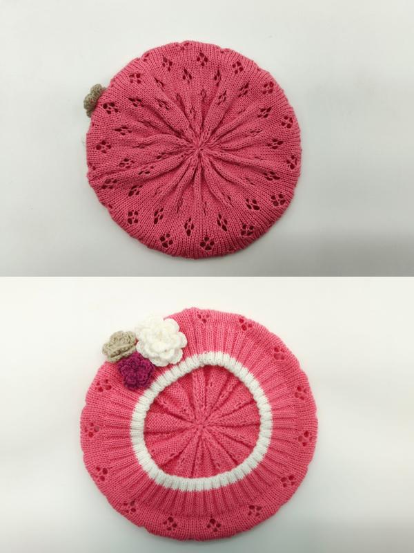 Pink knitted beret hat with eyelet lace pattern, white ribbed band, and three crochet flower appliqués in pink, white, and tan