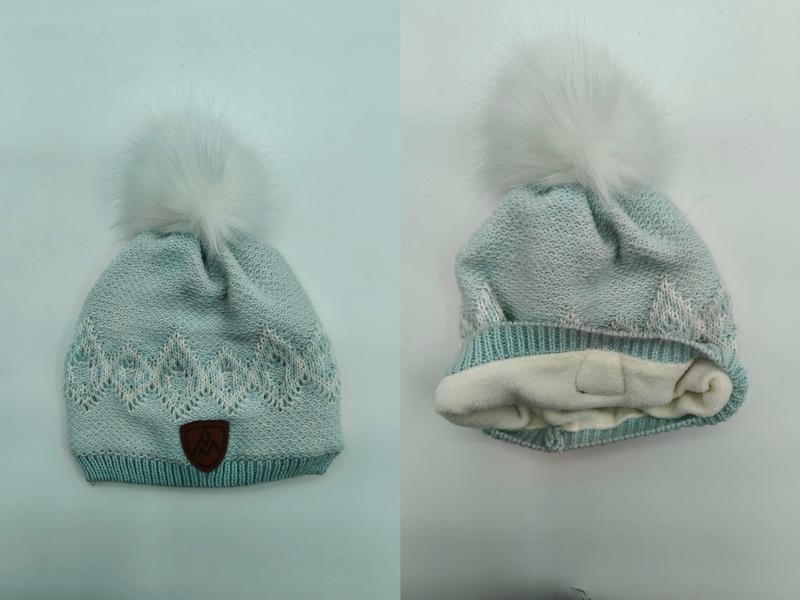 Mint green knit winter beanie with white faux fur pompom, jacquard pattern, fleece lining, and leather logo patch