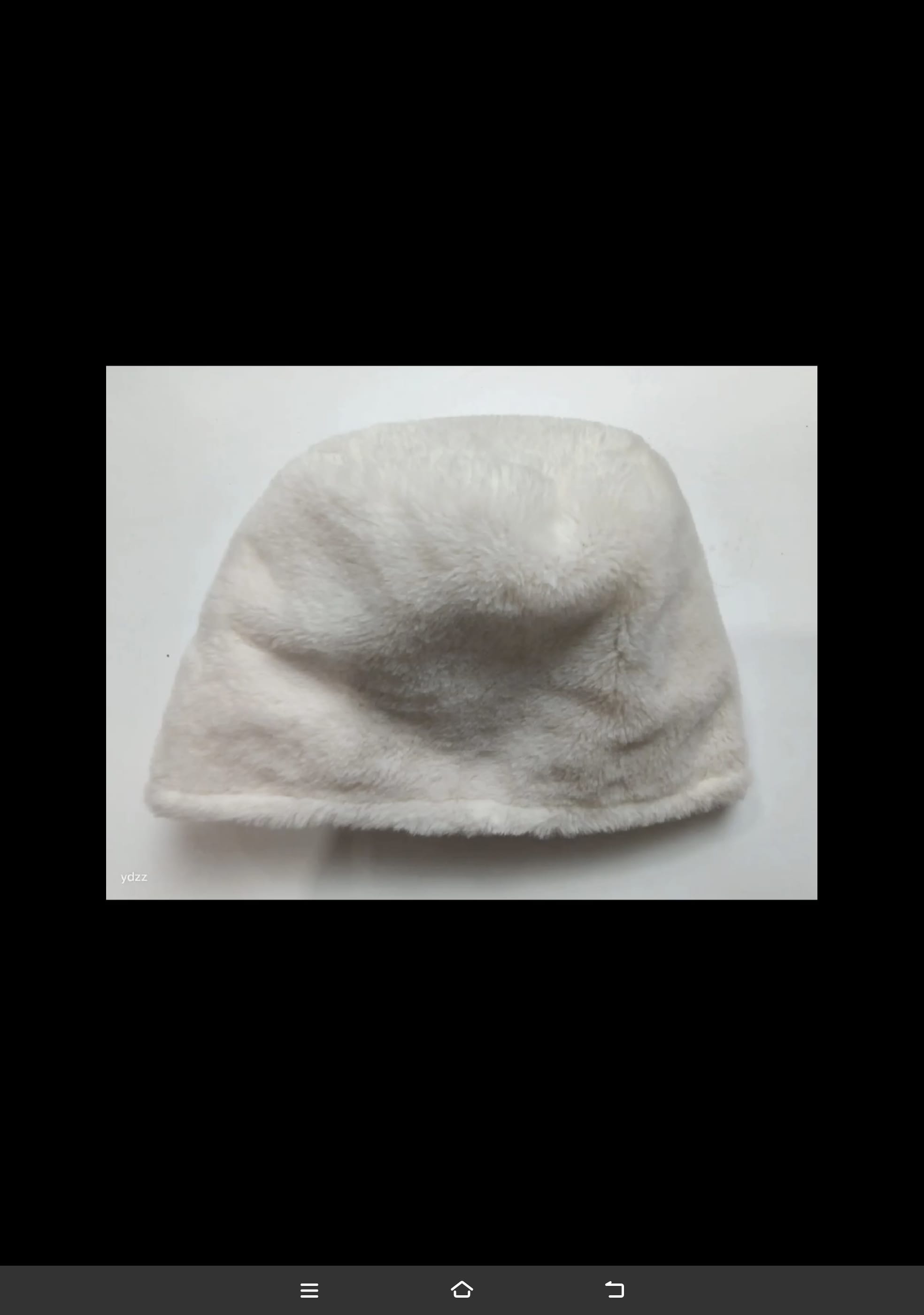 Cream white faux fur plush bucket hat laid flat on white surface, soft fluffy texture winter accessory