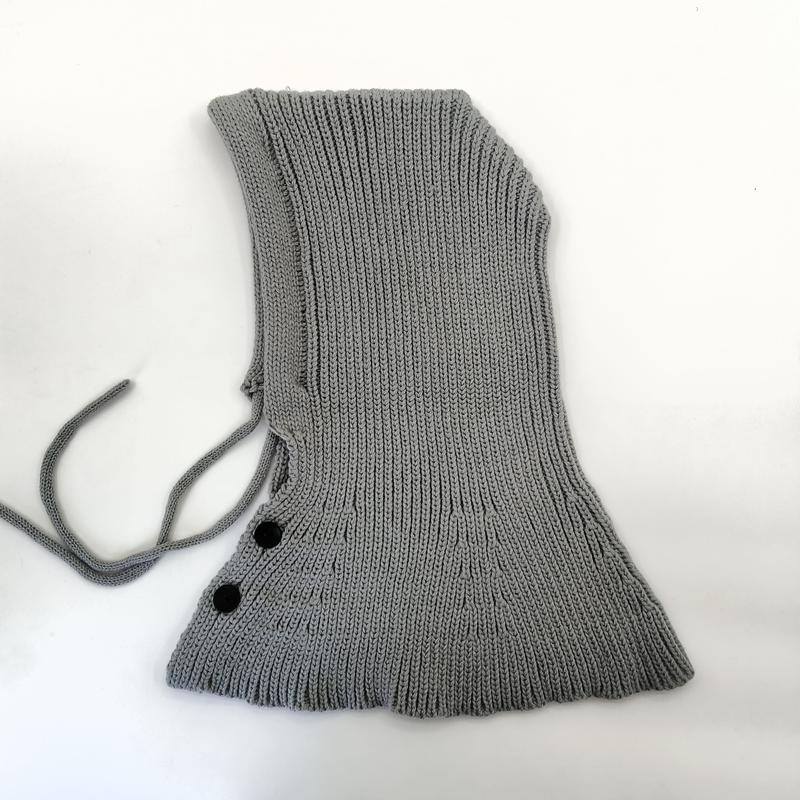 Grey ribbed knit balaclava hood with adjustable tie strings and two black button closures on white background