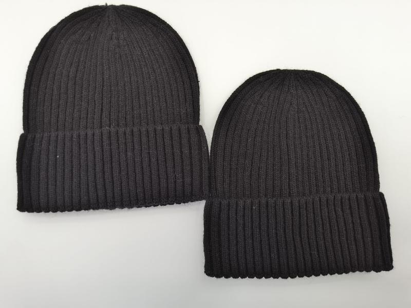 Two black ribbed knit cuffed beanie hats laid flat on white background, one larger and one smaller