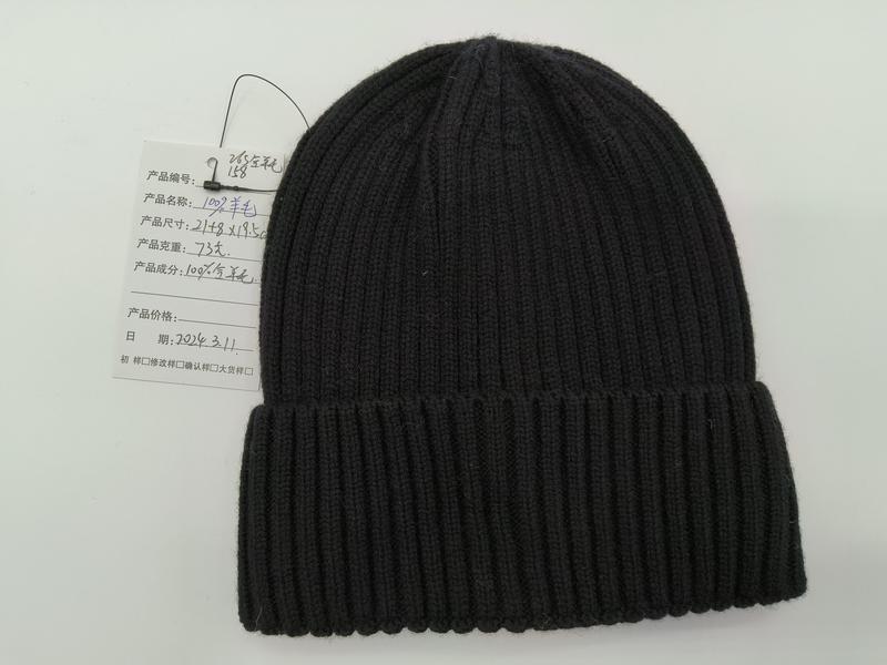 Black ribbed knit wool beanie hat with folded cuff displayed flat on white background with product tag