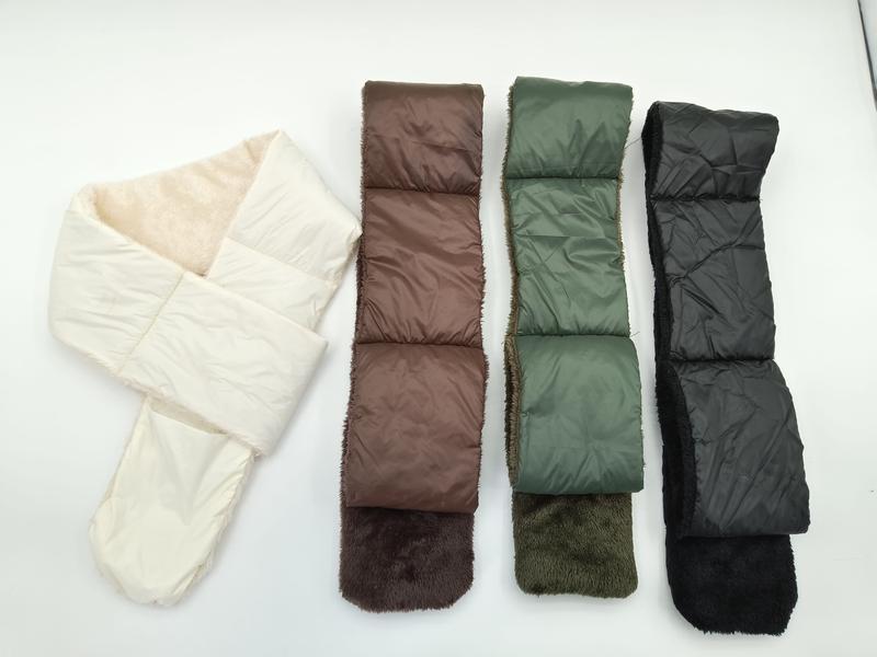 Four quilted puffer scarves with faux fur lining laid flat in cream, brown, olive green, and black colorways