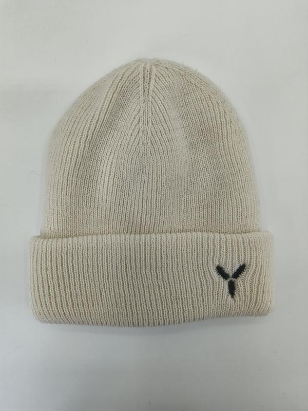 Cream ribbed knit beanie hat with folded cuff and small black embroidered Y logo, laid flat on white background