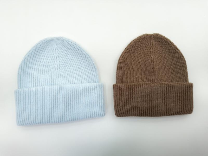 Two ribbed knit beanies side by side, one in baby blue and one in caramel brown, with folded cuffs on white background