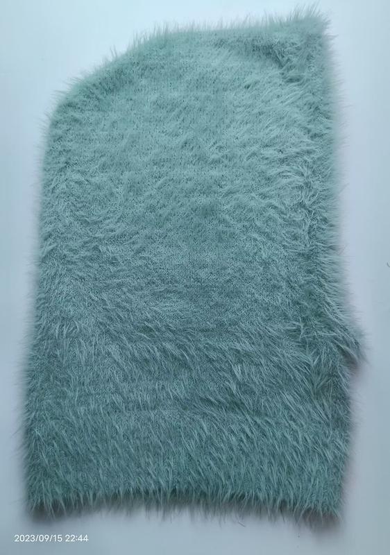 Mint green shaggy faux fur knit fabric swatch laid flat on white background, showing fluffy long-pile texture