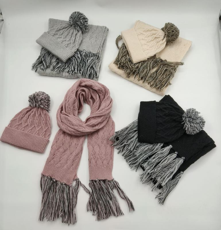 Four cable knit hat and scarf sets in grey, beige, pink, and black with pom pom beanies and tassel fringe scarves