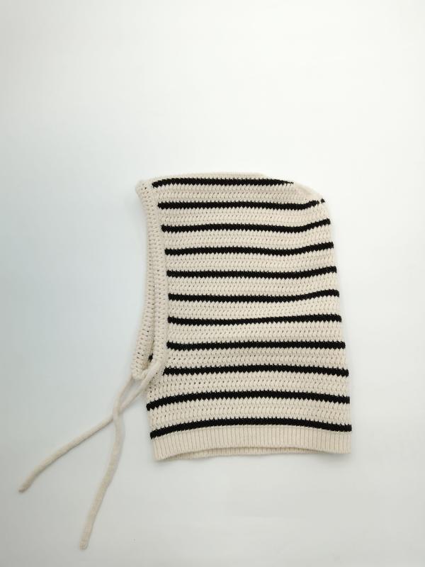 Cream and black horizontal striped crochet knit balaclava hood with tie strings, laid flat on white background