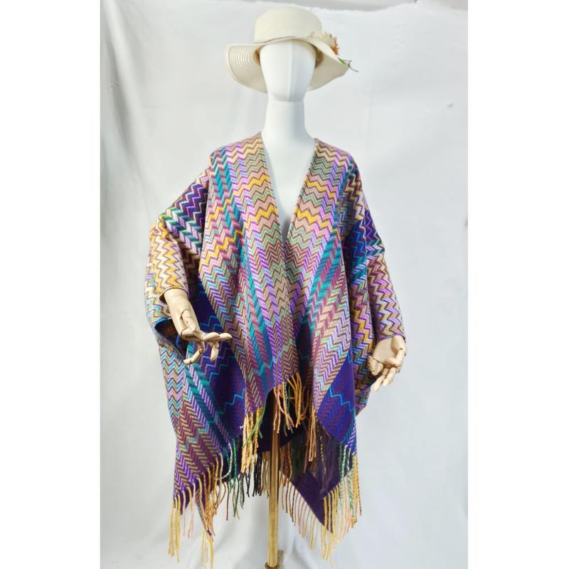 Mannequin wearing a multicolor chevron zigzag woven poncho wrap with long fringe trim and wide-brim hat