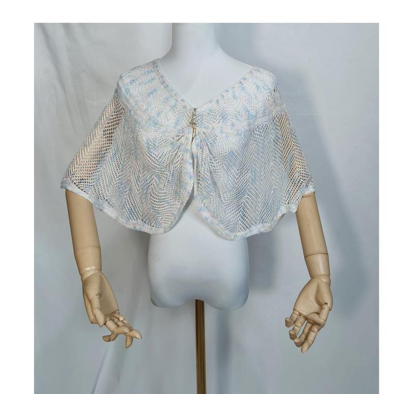 White and blue open-weave crochet mesh capelet with pearl brooch displayed on a dress form mannequin with wooden arms