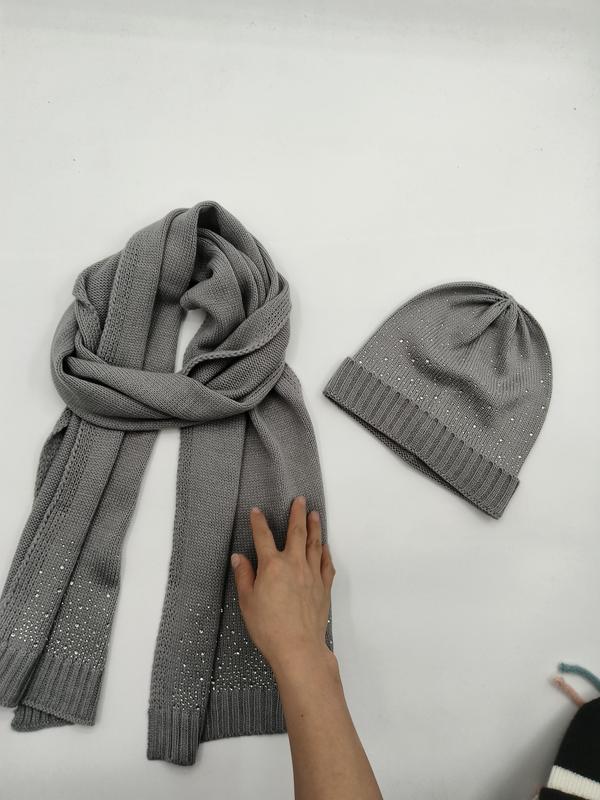 Grey knitted scarf and beanie hat set with scattered rhinestone embellishments laid flat on white surface