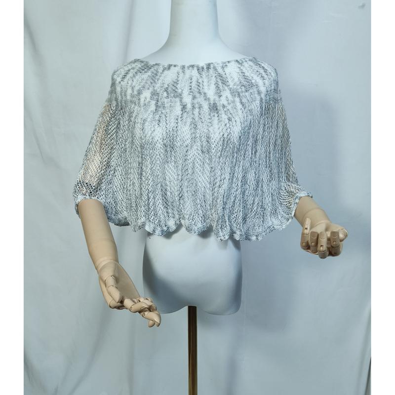 Gray and white open-knit lace crop poncho cape displayed on a mannequin with wooden artist hands, scalloped hem detail