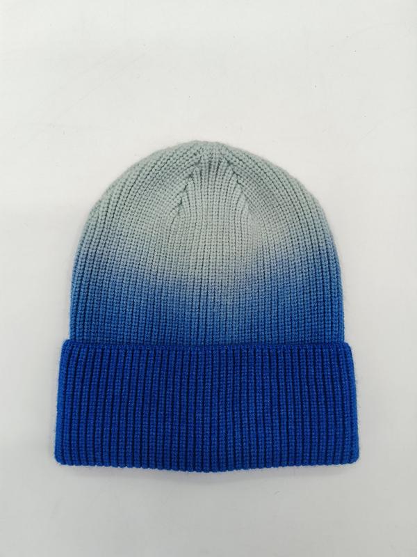 Ribbed knit cuffed beanie hat with blue to grey ombre dip-dye gradient effect, laid flat on white background