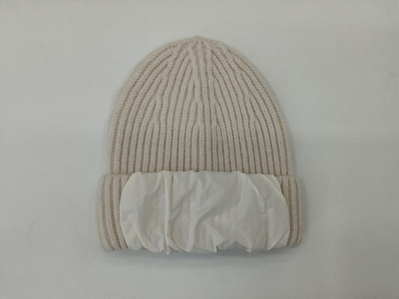 Cream ribbed knit winter beanie hat with white puffer fabric cuff band, flat lay on white background