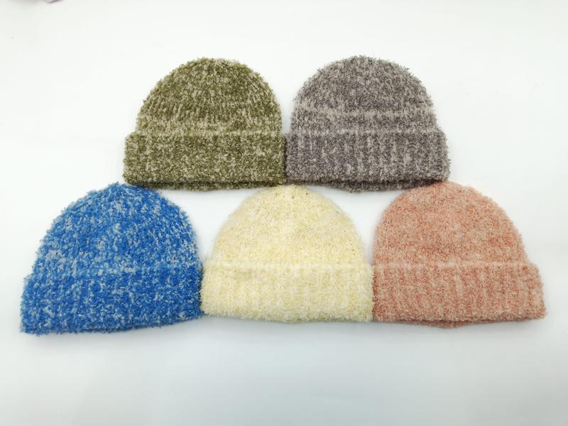 Five fuzzy bouclé knit beanie hats in olive green, gray, blue, cream, and dusty rose arranged on white background