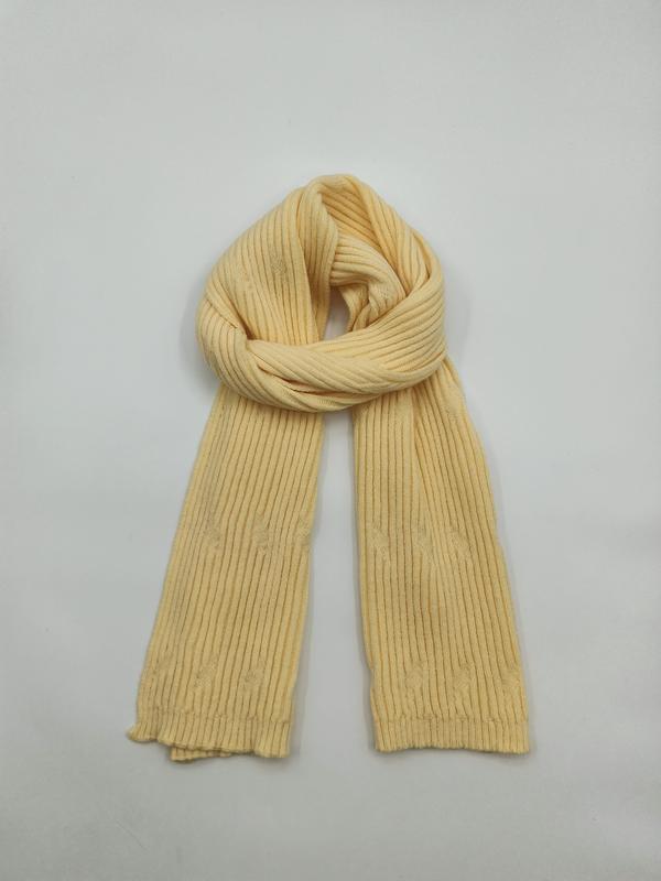 Pale yellow ribbed knit scarf looped and laid flat on white background, showing fine vertical rib texture