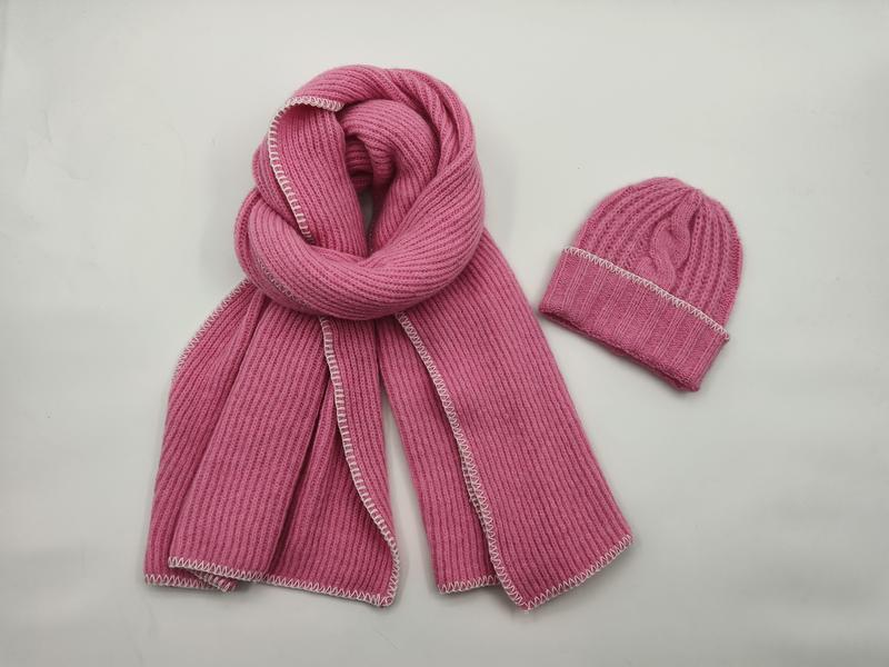 Pink ribbed knit winter scarf and matching beanie hat set with white contrast edge stitching on white background