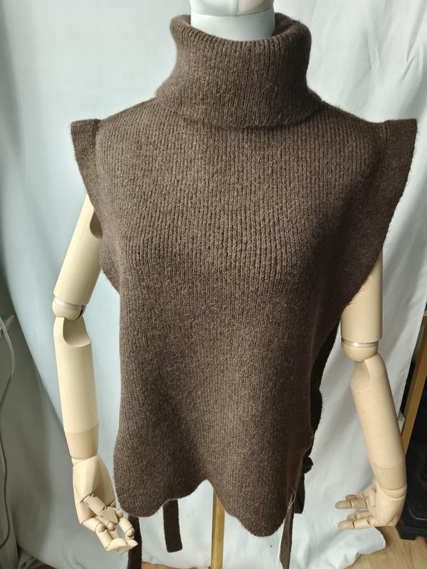 Brown chunky knit sleeveless turtleneck sweater vest with scalloped hem and side tie belt on mannequin