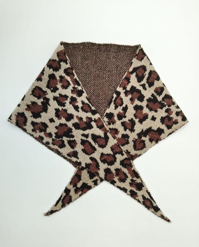 Reversible leopard print knit scarf with beige and brown animal pattern, crossed and laid flat showing textured brown reverse side